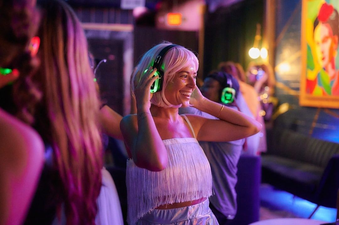 Vänner dansar med trådlösa hörlurar i färgstark belysning